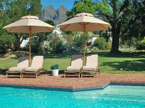 2 sillas y sombrillas junto a una piscina en 5 Mountains Lodge & Spa en Wellington