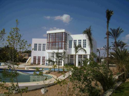 un grand bâtiment blanc avec une piscine et des palmiers dans l'établissement El Gouna dream villa sea front max13+3 people, à Hurghada