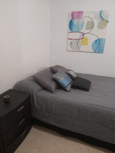 una camera da letto con letto con cuscini e comodino di Cozy Apartment across the San Juan Airport a San Juan