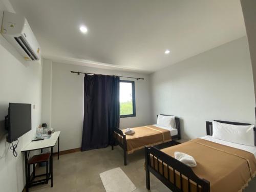a room with two beds and a desk and a window at Bakkahland Farm and Resort in Pattani