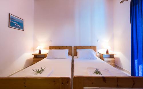 two beds in a room with two lamps on either side at Athena Studios in Vasilikos