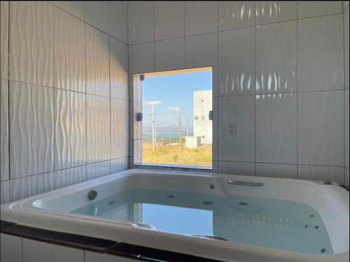 a bath tub in a tiled bathroom with a window at Casa com piscina Capitólio in Capitólio
