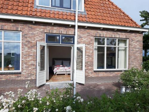 una casa de ladrillo con una puerta abierta con una cama en ella en Luxe gastenverblijf in het hart van Friesland, en Akkrum