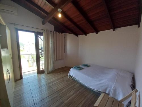 1 dormitorio con cama y ventana grande en Casa Orquídea - Ingleses Norte - 2º andar, en Florianópolis