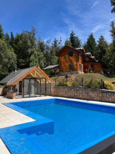 una grande piscina di fronte a una casa di tronchi di Portal del Manzano a Villa La Angostura