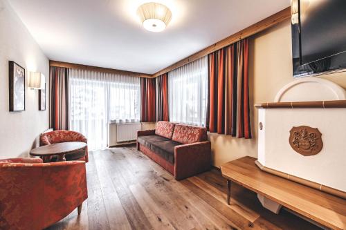 a living room with a couch and a tv at Hotel Rose in Mayrhofen
