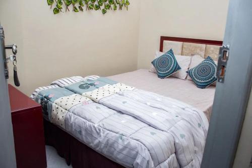 a bedroom with a bed with blue pillows at Hotel Kingdom Appartments in Mwanza