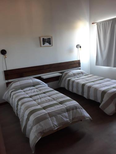 two beds in a white room with a bedskirts at El mejor descanso II in Plottier