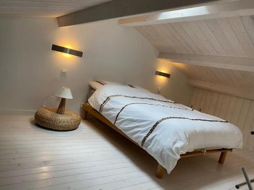 a bedroom with a bed and a lamp in a attic at La cabane de Lily - T2 classé 3 étoiles in Rochefort