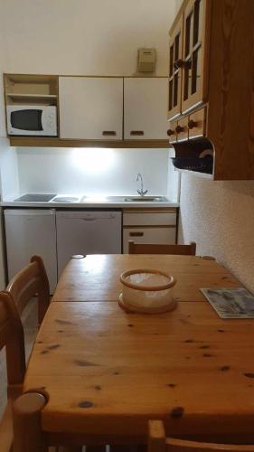 Il comprend une cuisine avec une table en bois et un évier. dans l'établissement Front de neige Panoramique, à Isola 2000