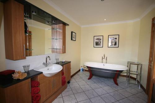 Un baño con dos lavabos y una bañera. en Ardmore luxury self catering cottage, en Broadford