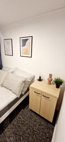 a bedroom with a bed and a wooden night stand at Apartamenty Daniłowskiego in Piotrków Trybunalski