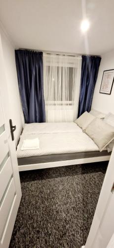 a bed in a small room with a window at Apartamenty Daniłowskiego in Piotrków Trybunalski