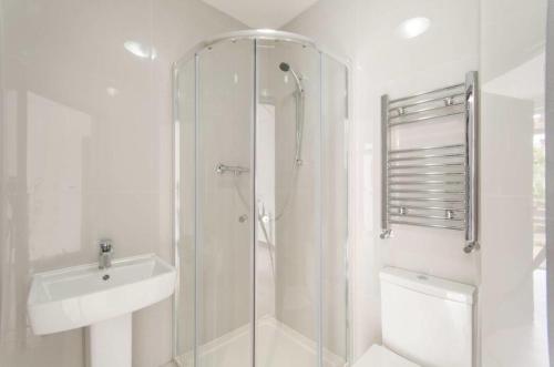 a white bathroom with a shower and a sink at City Riverview Apartment with Parking in London