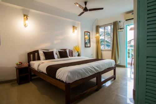 a bedroom with a bed and a ceiling fan at THE TURQUOIISE HOUSE in Morjim