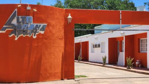 uma parede laranja com um sinal ao lado de um edifício em Apart Alto Parana em Paso de la Patria