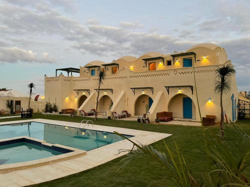 a large house with a swimming pool in front of it at Lake House by Tunisia Green Resort in Qaryat at Ta‘mīr as Siyāḩīyah