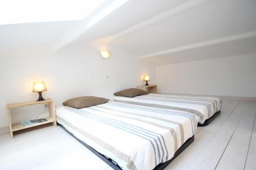 a white bedroom with two beds and two lamps at Le Clos des Flots - La Dune in La Flotte