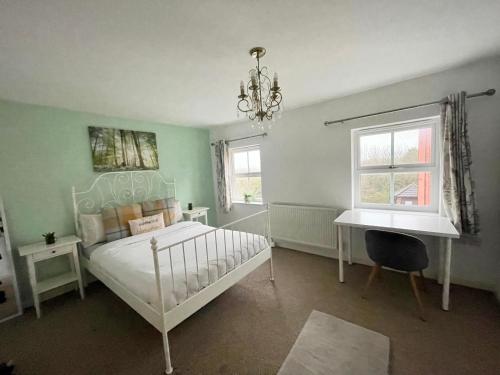 a bedroom with a bed and a desk and a chandelier at Wilce House in Wellingborough