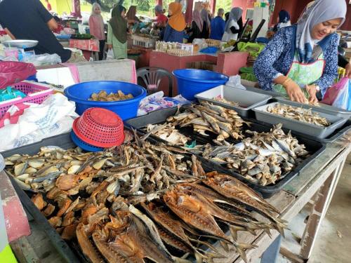 a woman standing next to a table filled with seafood at PCB PURPLE GUEST HOUSE in Kota Bharu