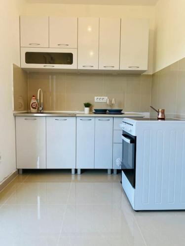 a kitchen with white cabinets and a stove top oven at Home Mia Airport in Podgorica