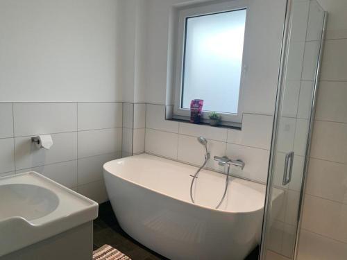 baño con bañera, lavabo y ventana en Beautiful modern country home, en Wegberg