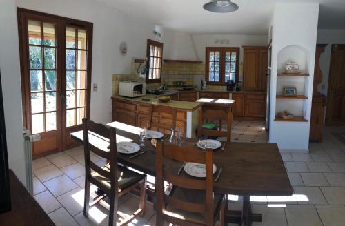une cuisine avec une table et des chaises en bois ainsi qu'un astérisque dans l'établissement La maison des Sources, à Salon-de-Provence