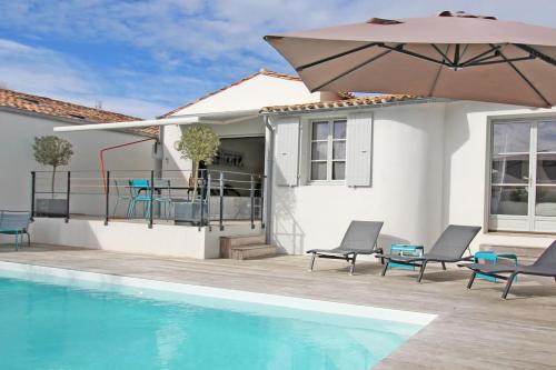 une piscine avec des chaises et un parasol à côté d'une maison dans l'établissement La Villa des Flots, à La Flotte