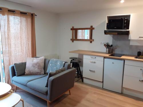 un salon avec un canapé et une cuisine dans l'établissement ELLIE, à Lanester