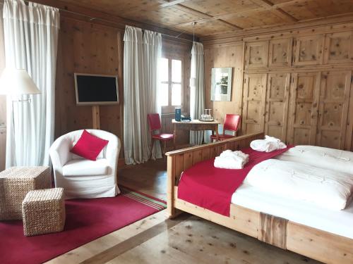 a bedroom with a bed and a chair and a desk at Palazzo Mysanus Samedan in Samedan