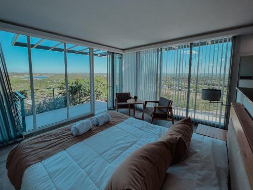 sypialnia z dużym łóżkiem i dużymi oknami w obiekcie Altos de Los Paraísos Vista al lago y sierras w mieście Juana Koslay 