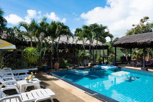 a pool at a resort with white chairs and palm trees at Harmony Naturist Resort Rawai Phuket 18yr minimum age only nudist nake d FKK in Rawai Beach