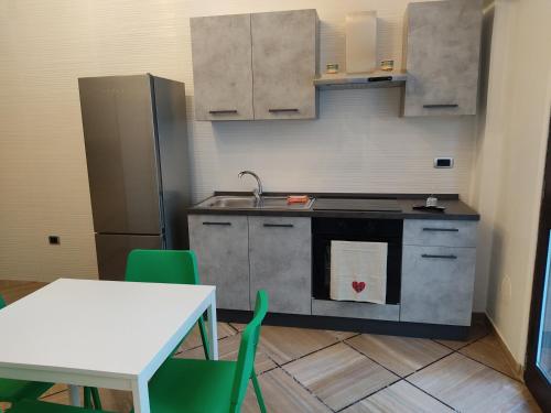 Il comprend une cuisine équipée d'une cuisinière et d'une table avec des chaises vertes. dans l'établissement Domus vacanze Alfieri, à Manfredonia