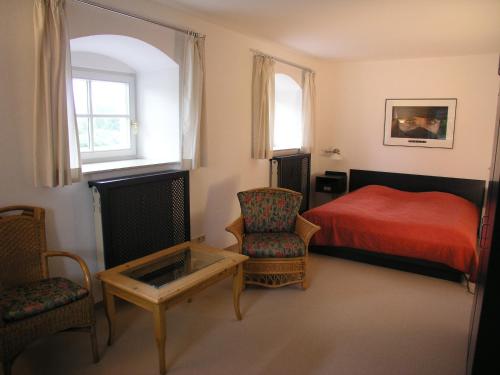 um quarto com uma cama vermelha e uma cadeira em Haus Rufinus am Kloster Seeon em Seeon-Seebruck