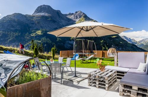 un patio con mesa, sombrilla y montañas en Haus Schrofenwies, en Lechleiten