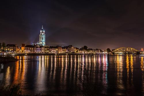 a city with a clock tower and a river at night at Kleinschalig Hostel in Deventer, centrum stad, aan de IJssel, in Deventer