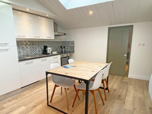 - une cuisine avec une table en bois et des chaises blanches dans l'établissement L'appart' Le Bois Flotté, au Bois-Plage-en-Ré