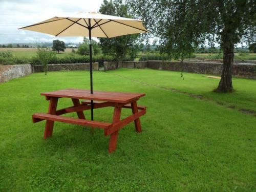 a picnic table with an umbrella on the grass at Bungalow in lovely setting.Ten minutes to Longleat in North Bradley