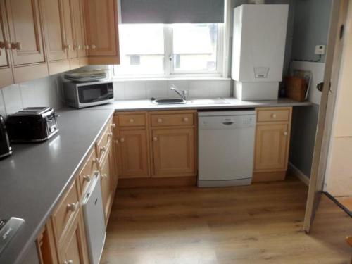 a kitchen with wooden cabinets and a white refrigerator at Bungalow in lovely setting.Ten minutes to Longleat in North Bradley