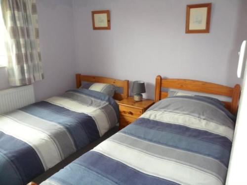 two beds sitting next to each other in a bedroom at Bungalow in lovely setting.Ten minutes to Longleat in North Bradley