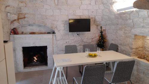 a stone wall with a table and a fireplace at Trullo Scrascia. in Ceglie Messapica