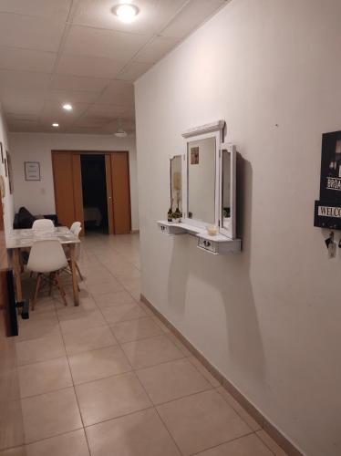 Cette chambre dispose d'un mur blanc, d'une table et de chaises. dans l'établissement Studio Puerto Escobar, 2 ambientes, à Belén de Escobar