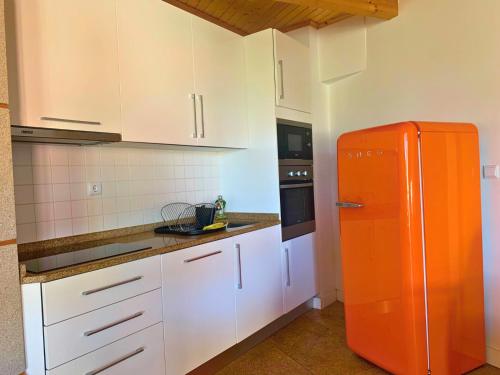 una nevera naranja en una cocina con armarios blancos en Casas d Aldeia Turismo Rural, en Mangualde