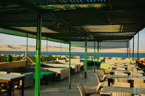 a restaurant with tables and chairs and a view of the ocean at Lake House by Tunisia Green Resort in Qaryat at Ta‘mīr as Siyāḩīyah
