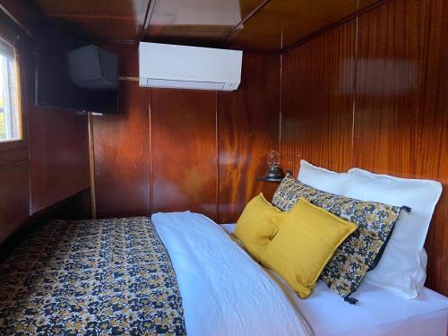 1 dormitorio con cama y almohadas en un barco en Studio sur la péniche Santa Julia à Chantilly Insolys en Saint-Leu-dʼEsserent