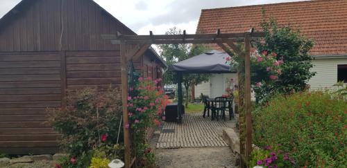 un jardin avec une pergola en bois et des fleurs dans l'établissement Chalet insolite, à Saint-Georges-de-Livoye