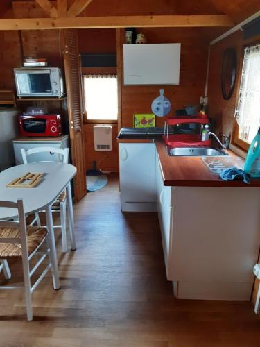une petite cuisine avec un évier et une table dans l'établissement Chalet insolite, à Saint-Georges-de-Livoye