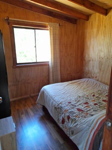 a bedroom with a bed in a room with a window at Cabaña Radal C/ Tinaja in Los Lagos