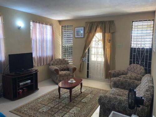 uma sala de estar com um sofá e cadeiras e uma televisão em DonaMae 2 story Barbados House em Bridgetown