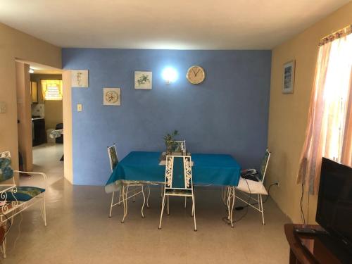 una mesa y sillas en una habitación con una pared azul en DonaMae 2 story Barbados House en Bridgetown